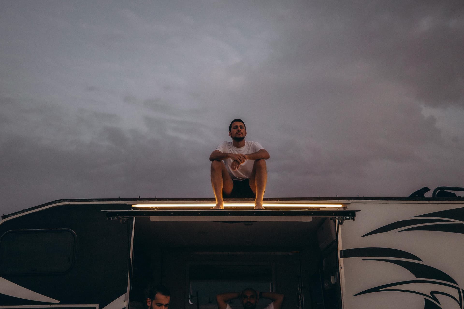 guy sitting on car roof staring in the sky